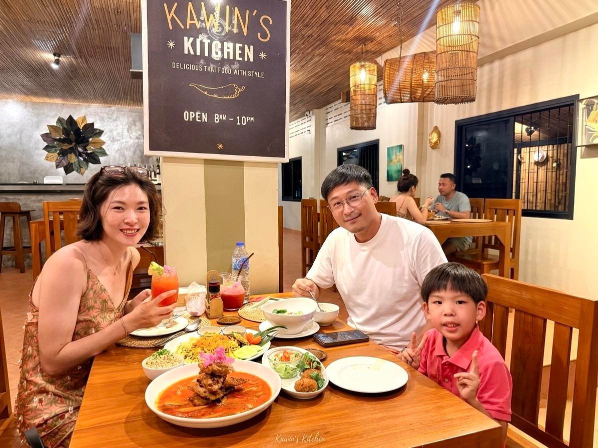 Family of three dining at Kamijns Kitchen restaurant, with traditional dishes and beverages on wooden table